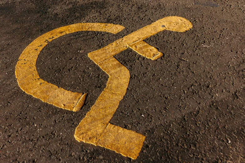 a yellow sign sitting on the side of a road, by Adam Marczyński, accessible for the disabled, glagolitic glyph, textured, spaghettification