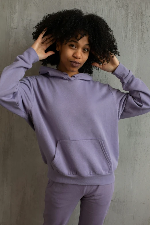 a woman standing in front of a wall wearing a purple hoodie, wearing a grey hooded sweatshirt, thumbnail, soft cool colors, ((purple))