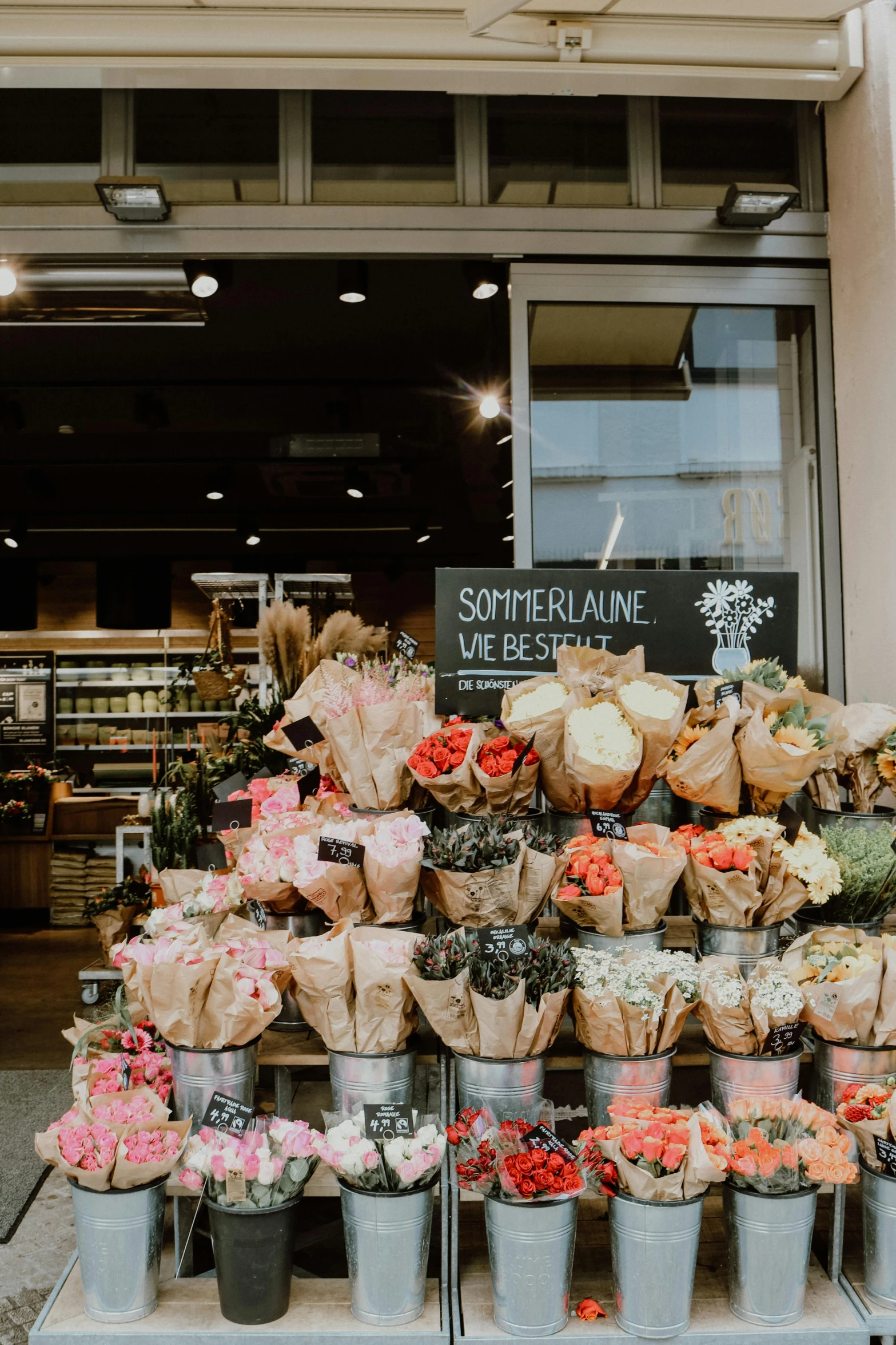 a bunch of buckets of flowers in front of a store, a picture, by Jens Søndergaard, unsplash, inside a supermarket, black and terracotta, bakery, view from the bottom