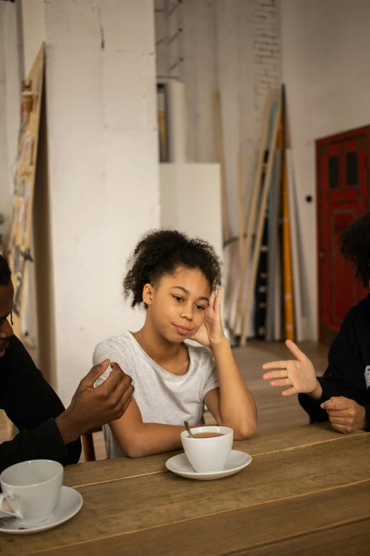 a group of people sitting around a wooden table, black teenage girl, confounding, coffee, family friendly