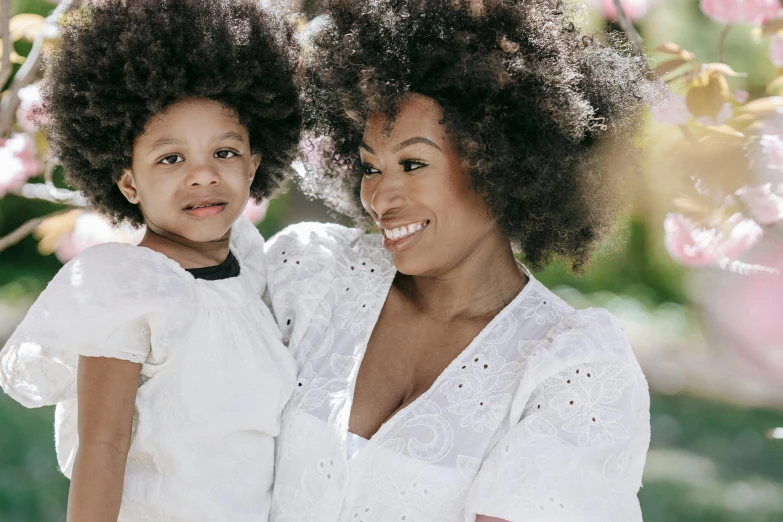 a woman holding a little girl in her arms, a portrait, by Lily Delissa Joseph, pexels contest winner, with afro, white, avatar image, manuka