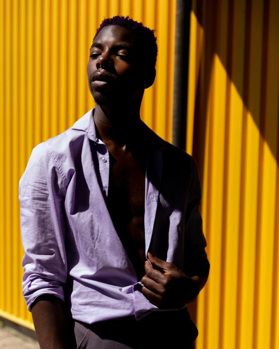 a man standing in front of a yellow wall, by Cosmo Alexander, trending on unsplash, black arts movement, ((purple)), non binary model, summer morning light, adut akech