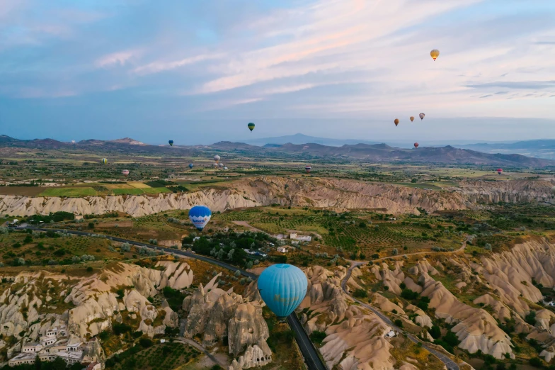 a group of hot air balloons flying over a valley, by Daren Bader, pexels contest winner, ancient marble city, thumbnail, conde nast traveler photo, wide aerial shot