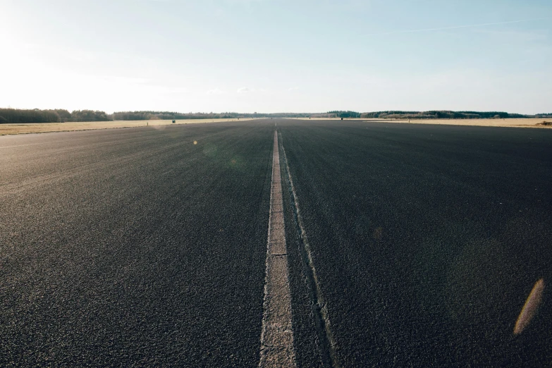 a man riding a skateboard on top of an airport tarmac, by Thomas Häfner, unsplash, postminimalism, roads among fields, germany. wide shot, vast expanse, a long-shot from front