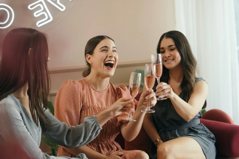 a group of women sitting on top of a couch holding wine glasses, pexels contest winner, happening, pink, three women, casually dressed, milk bar magazine