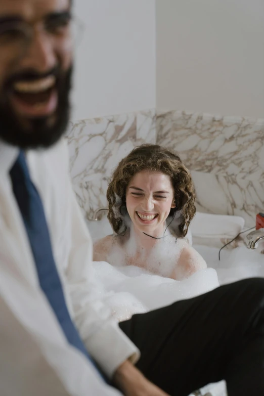 a man sitting on top of a bed next to a woman, by Anita Malfatti, trending on unsplash, renaissance, bubble bath, laughing groom, alison brie, ignant