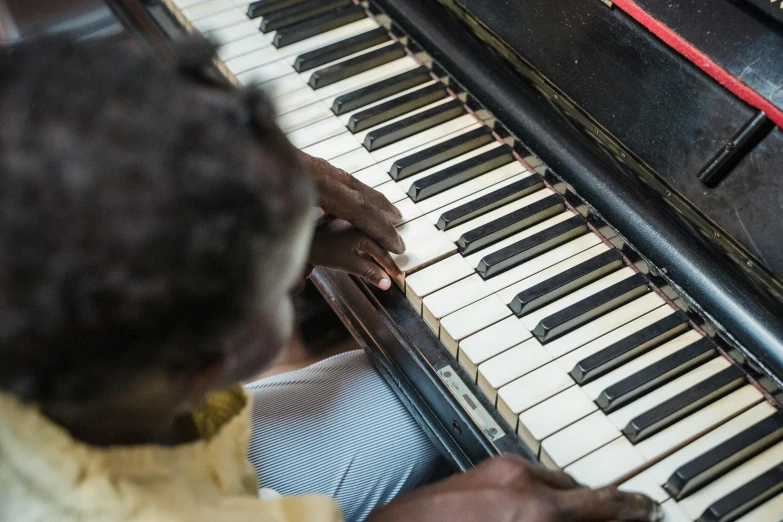 a close up of a person playing a piano, black arts movement, restoration, adut akech, colour photograph, top - down photograph