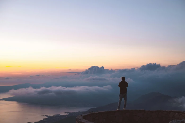 a man standing on top of a mountain next to the ocean, by Niko Henrichon, pexels contest winner, romanticism, view above the clouds, avatar image, watching the sunset, full body profile