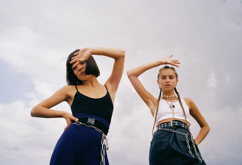 a couple of women standing next to each other, trending on pexels, realism, as fashion editorial 90s, bandoliers, skies, chains on hands