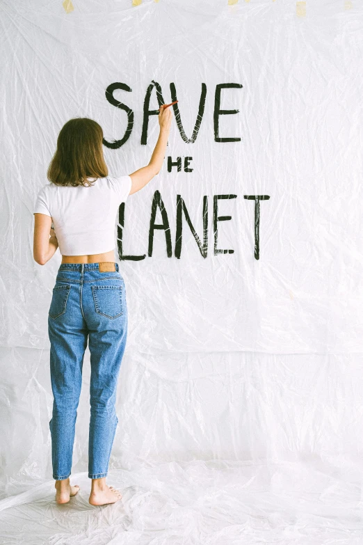 a woman writing save the planet on a wall, trending on pexels, crop top, promotional image, m