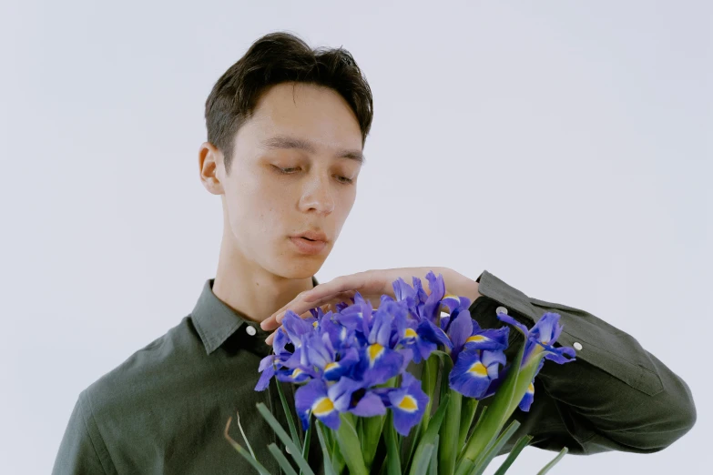 a man holding a bouquet of purple flowers, an album cover, inspired by Fei Danxu, cheekbones, focus on iris, taken with sony alpha 9, kiko mizuhara