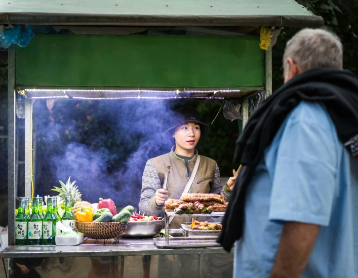 a man standing in front of a food stand, by Julia Pishtar, unsplash, barbecue, square, lee madgwick & liam wong, ukrainian