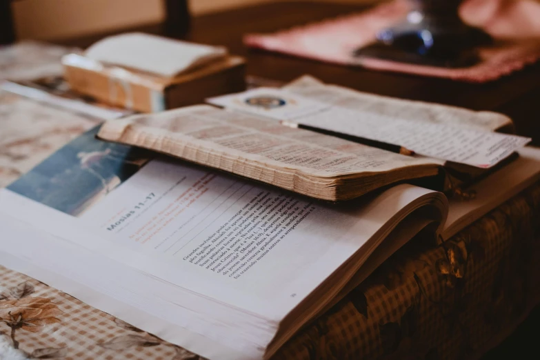 an open book sitting on top of a bed, unsplash, academic art, found papers, on a coffee table, background image, biblical image