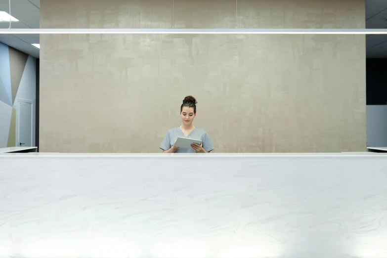 a woman sitting at a desk using a cell phone, a minimalist painting, inspired by Fei Danxu, hospital, white marble interior photograph, 4k post, ignant