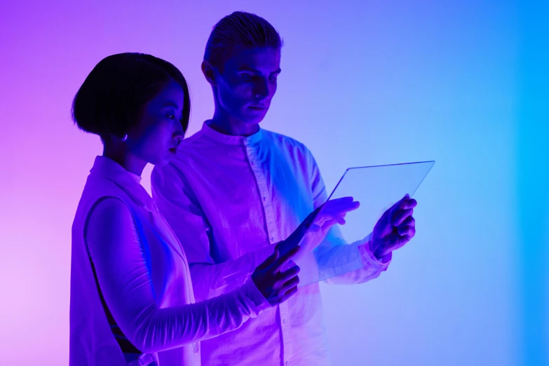 a man and woman looking at a tablet computer, a hologram, pexels, interactive art, purple scene lighting, scientist, photoshoot, ruan jia and michael komarck