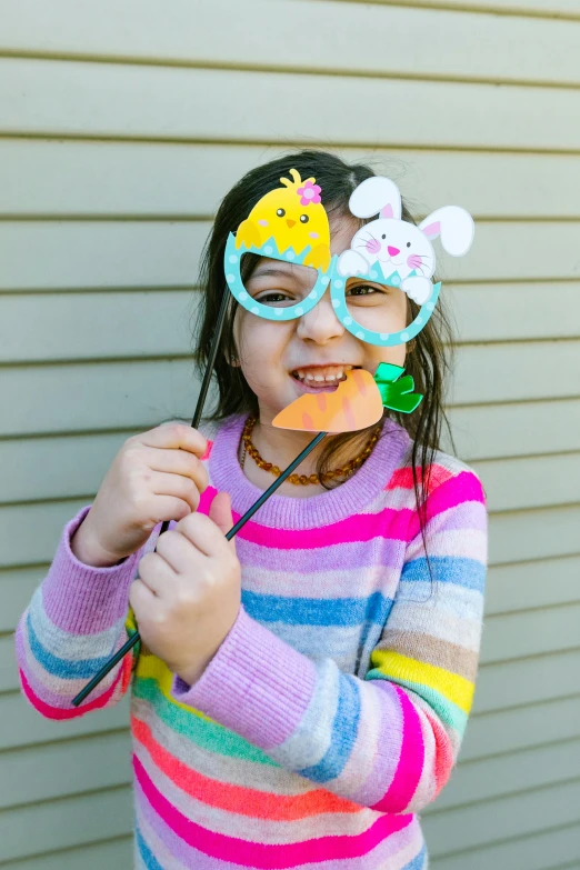 a young girl holding a piece of paper in front of her face, instagram, holding easter eggs, ar glasses, photo booth, profile image