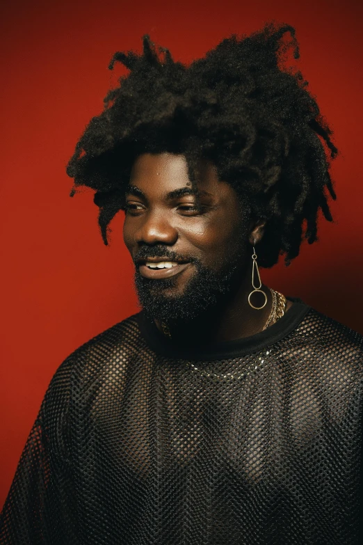 a man with dreadlocks standing in front of a red wall, an album cover, inspired by Charles Martin, black man with afro hair, on grey background, sly smile, black panther