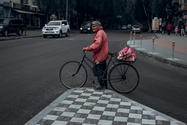 a man standing next to a bicycle on a street, by Attila Meszlenyi, pexels contest winner, realism, chessboard scientist, ukraine. photography, purple checkerboard, an old lady