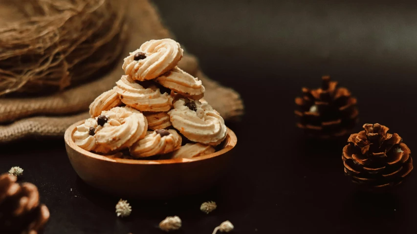 a wooden bowl filled with cookies on top of a table, trending on pexels, baroque, background image, pinecone, lecherous pose, stacked image