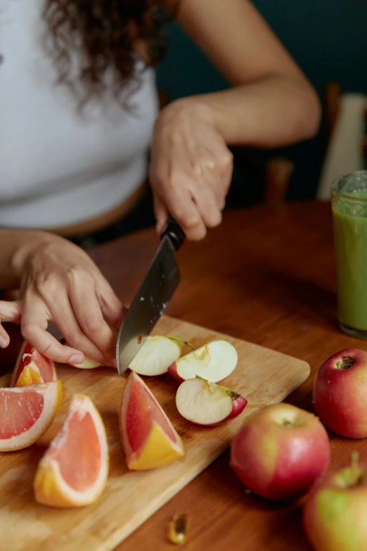 a woman cutting up a grapefruit on a cutting board, by Julian Allen, colourful apples, cinematic shot, switch