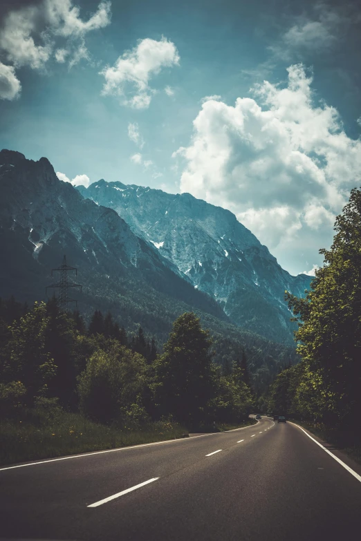 an empty road with mountains in the background, unsplash contest winner, visual art, trees and cliffs, chamonix, skies behind, chemistry