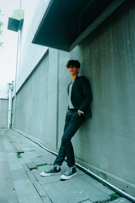 a man leaning against a wall in front of a building, an album cover, inspired by Joong Keun Lee, unsplash, full body profile pose, jc park, profile image, shinichi sakamoto