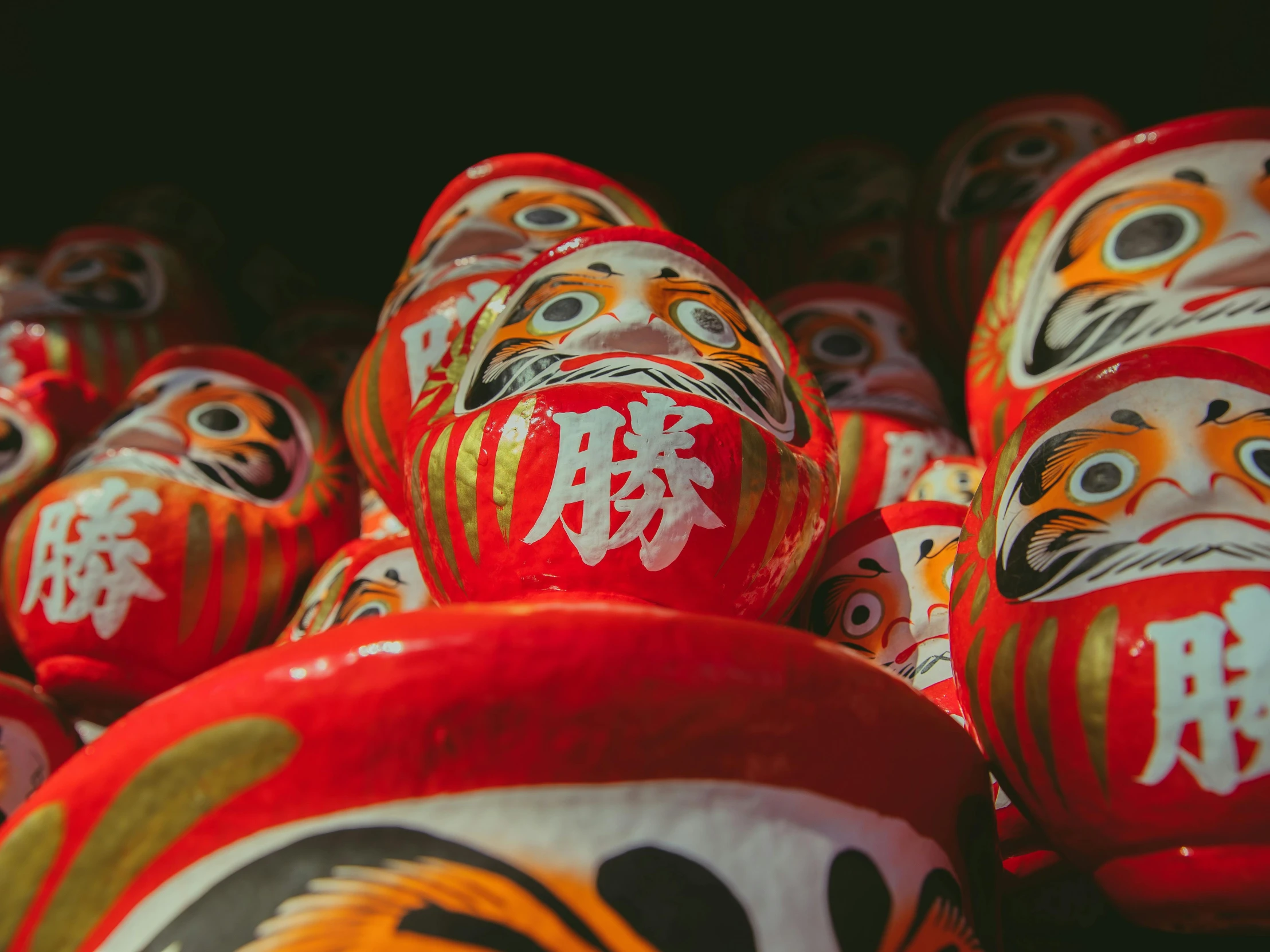 a group of red and white dolls sitting on top of each other, mingei, red black and gold color scheme, intricate faces, 🦩🪐🐞👩🏻🦳, top selection on unsplash