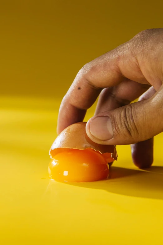 a person is peeling an egg on a yellow surface, by Doug Ohlson, trending on pexels, hyperrealism, made of wax and water, 15081959 21121991 01012000 4k, orange subsurface scattering, smooth detailed