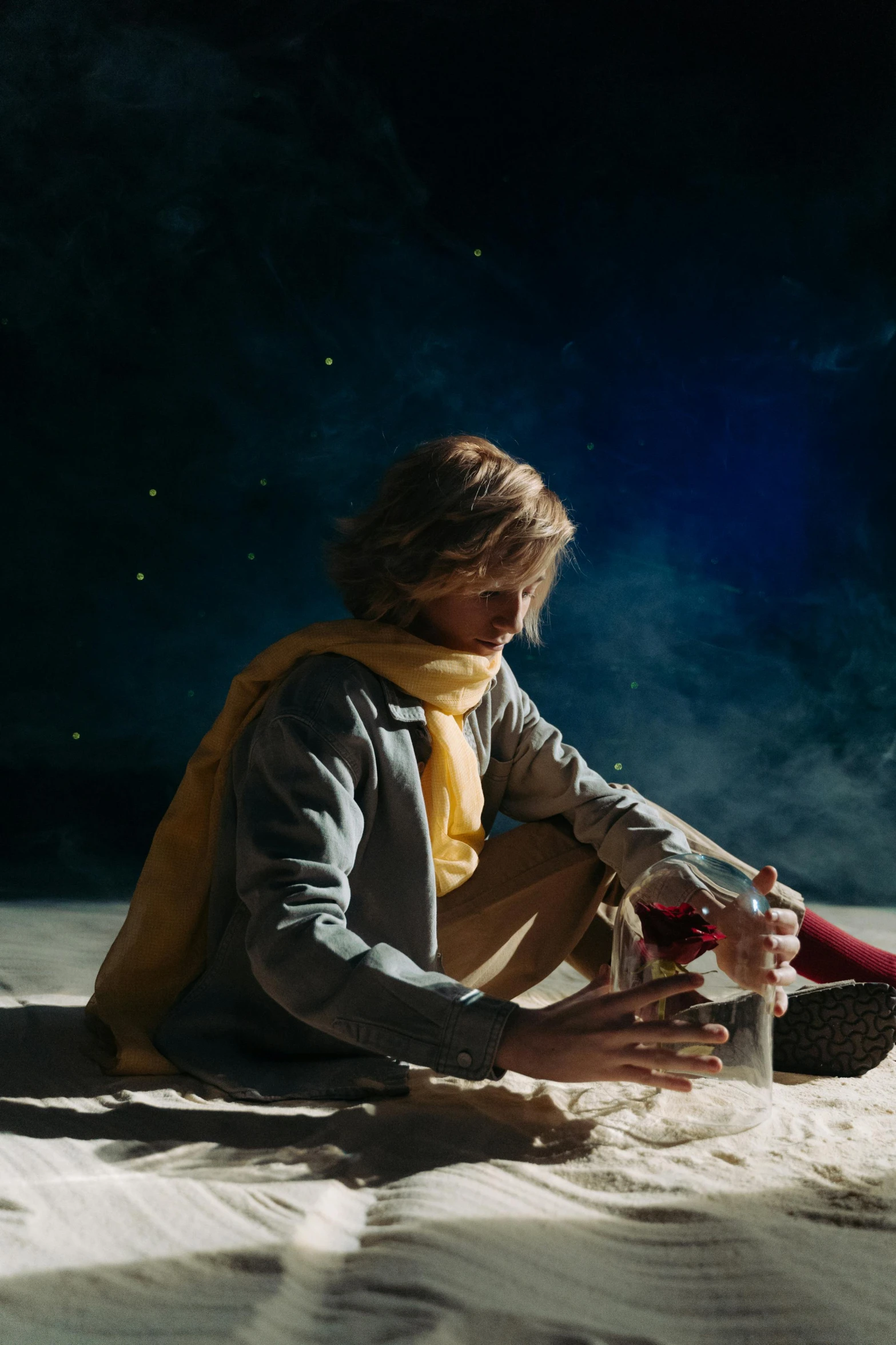 a man sitting on top of a sandy beach, an album cover, trending on pexels, magical realism, jamie campbell bower, arabian nights, okita sougo, standing in outer space