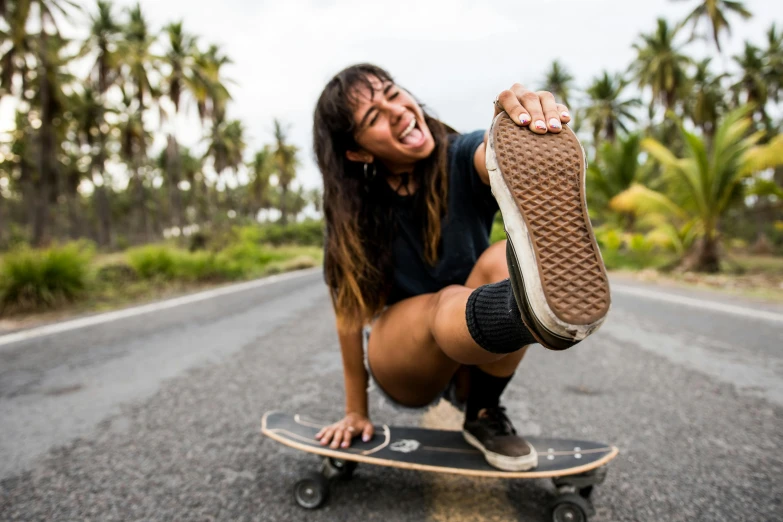 a woman sitting on top of a skateboard on a road, wide grin, gum rubber outsole, samoan features, as well as scratches