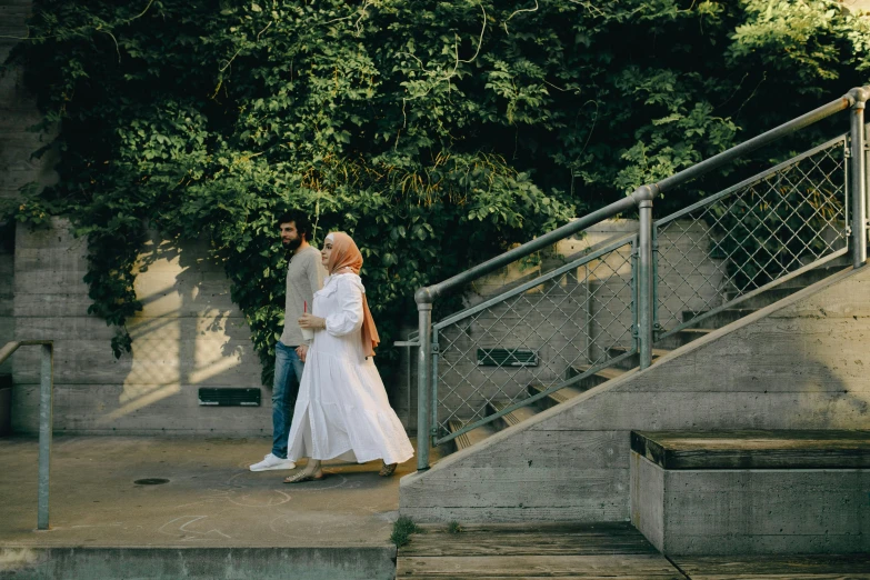 a man and a woman walking down a set of stairs, pexels contest winner, happening, white hijab, at the park, ( ( theatrical ) ), fan favorite