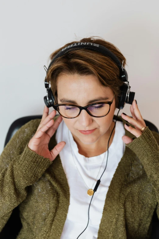 a woman sitting in a chair with headphones on, trending on pexels, renaissance, nerdy music teacher with phd, sitting at a control center, subtle wear - and - tear, uncropped