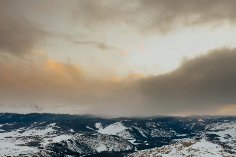 a man riding a snowboard on top of a snow covered slope, by Emma Andijewska, pexels contest winner, visual art, cloudy sunset, colorado mountains, panorama view, overcast