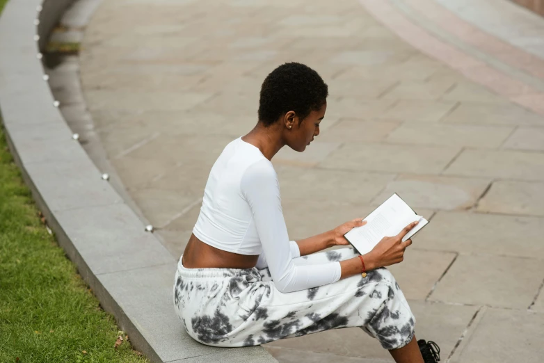 a woman sitting on a curb reading a book, by Alice Mason, pexels contest winner, wearing crop top, kara walker, full body length, maria borges