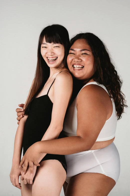 a couple of women standing next to each other, inspired by Wang Duo, trending on pexels, she has a jiggly fat round belly, ethnicity : japanese, supermodel, laughing