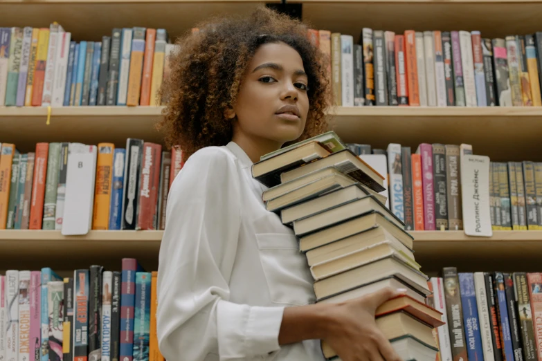 a woman holding a stack of books in front of a bookshelf, pexels contest winner, with afro, handsome girl, large)}], casually dressed
