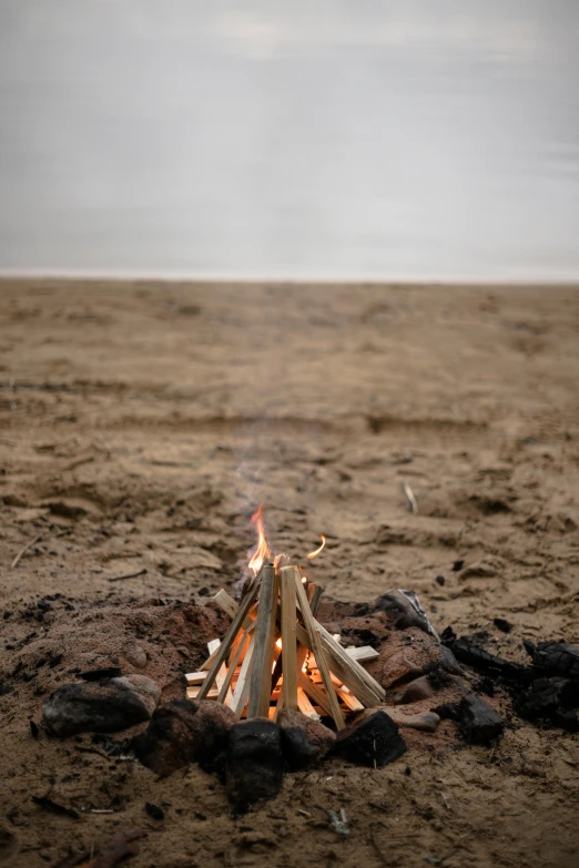 a campfire sitting on top of a sandy beach, a picture, unsplash, land art, multiple stories, iceland, detail shot, a wooden