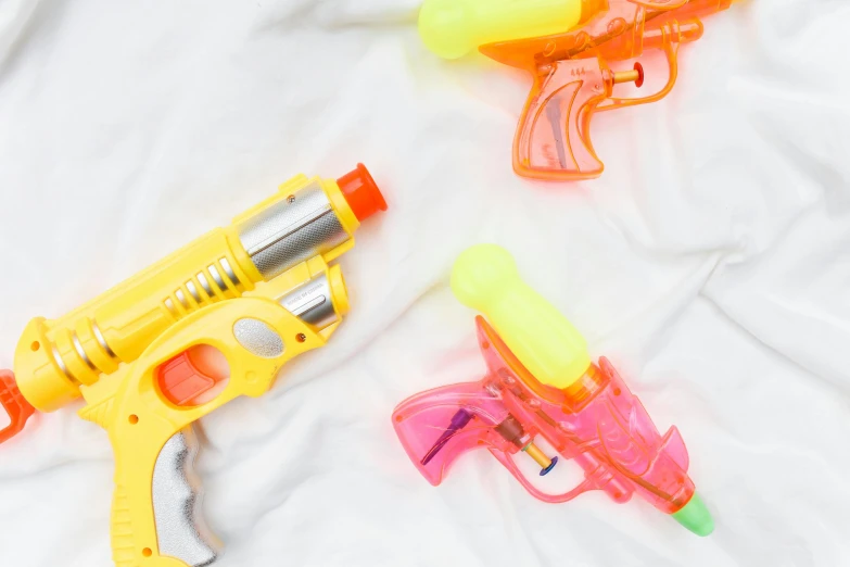 a couple of water guns laying on top of a bed, pexels, instagram post, background image, white background, neons