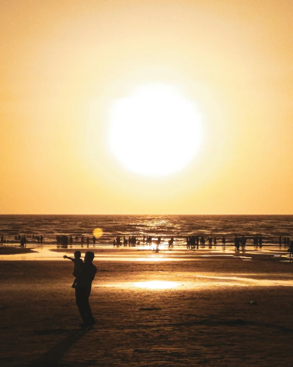 a person flying a kite on a beach at sunset, by Jan Tengnagel, pexels contest winner, lgbtq, gigantic sun, snapchat photo, hot and humid