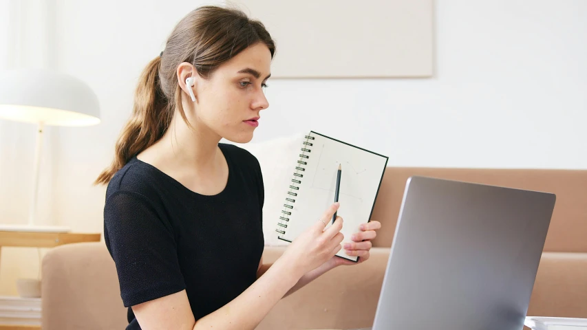 a woman sitting on a couch using a laptop computer, by Nicolette Macnamara, trending on pexels, holding microphone, schematic in a notebook, woman with braided brown hair, slightly minimal