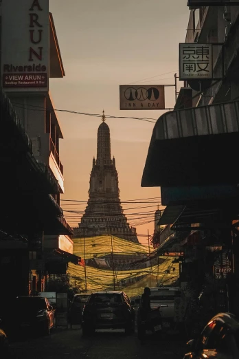 a street filled with lots of traffic next to tall buildings, by Max Buri, unsplash contest winner, thai temple, low sun, square, brown