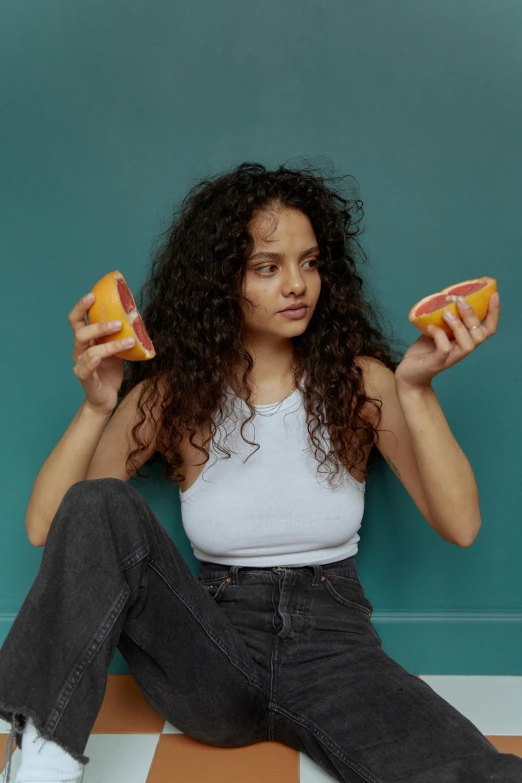 a woman sitting on the floor holding two oranges, trending on pexels, renaissance, serving burgers, curly hair, non binary model, mixed race