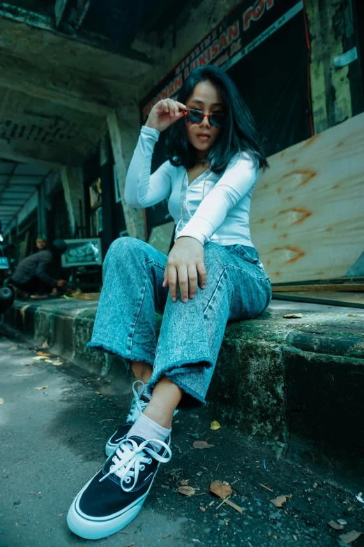 a woman sitting on the steps of a building, by Basuki Abdullah, trending on pexels, realism, baggy jeans, wear ray - ban glass, 90's photo, federation clothing