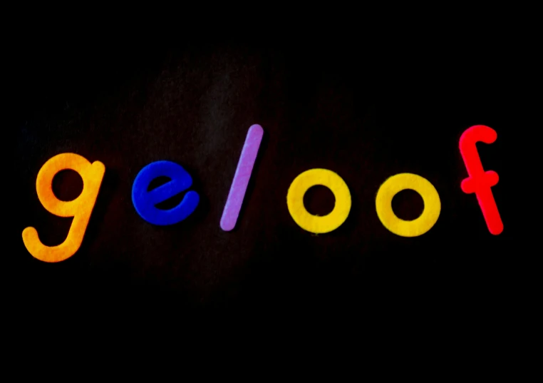 a close up of the word fool on a black background, pexels, neogeo, made of lollypops, goodnight, google logo, wooden jewerly