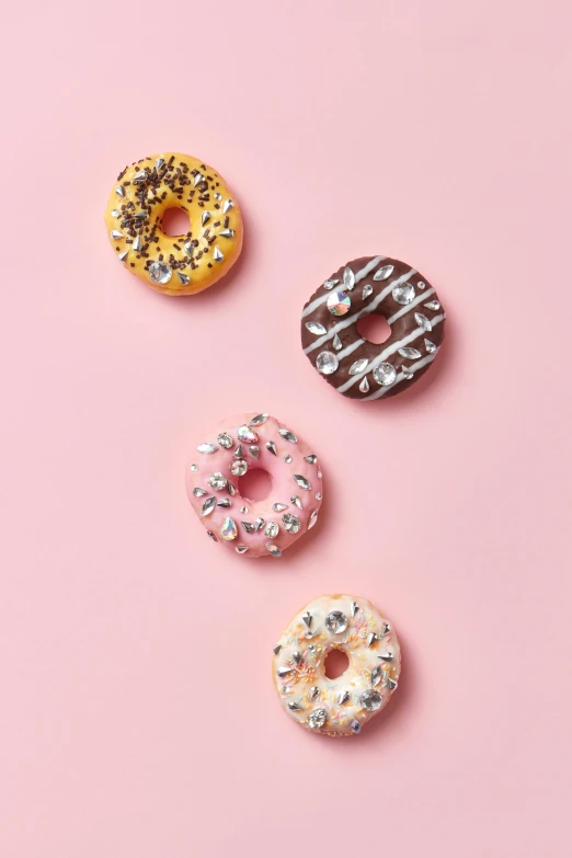 donuts with sprinkles on a pink background, inspired by david rubín, floating metallic objects, with sparkling gems on top, 4 colors, glazed ceramic