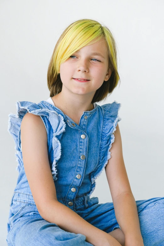 a young girl sitting on the floor in a denim dress, medium yellow blond hair, head shot, full product shot, zoomed in