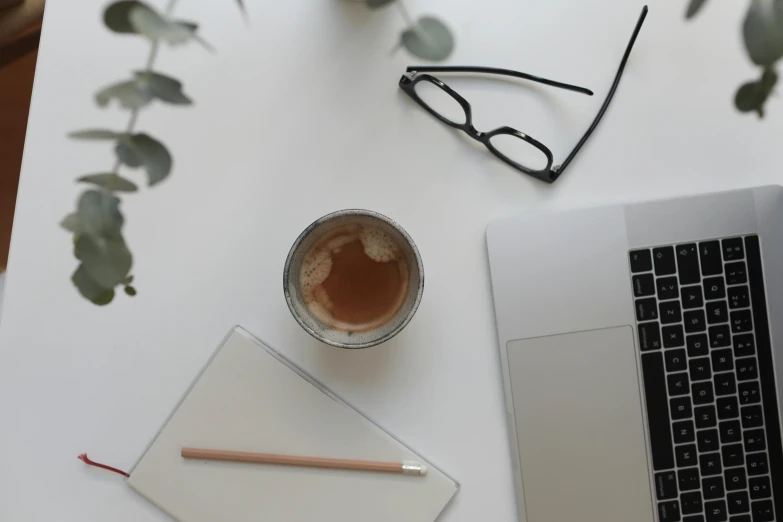 a laptop computer sitting on top of a table next to a cup of coffee, by Carey Morris, minimalism, square rimmed glasses, white backround, looking down on the camera, intricate image