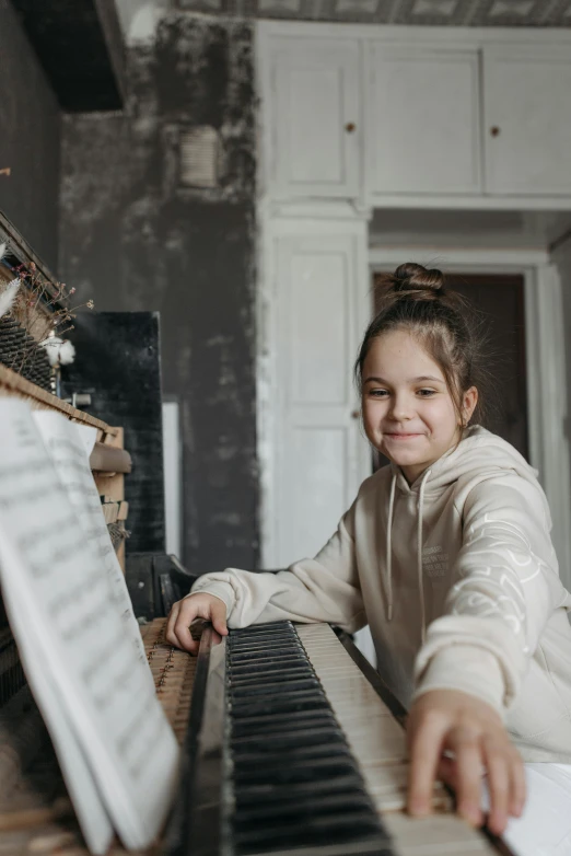 a little girl sitting in front of a piano