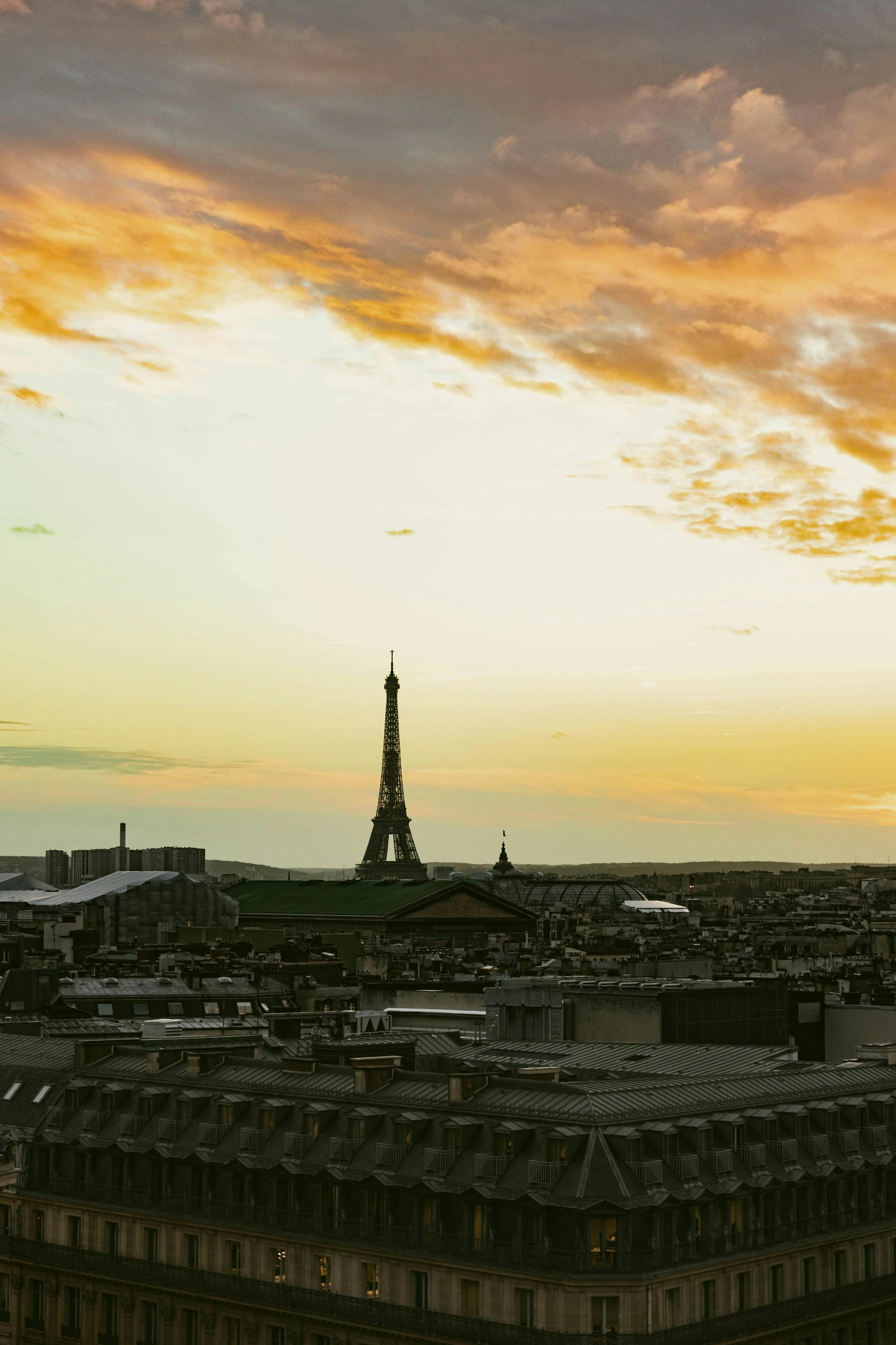 a view of the eiffel tower from the top of a building, patches of yellow sky, on a rooftop, sprawling