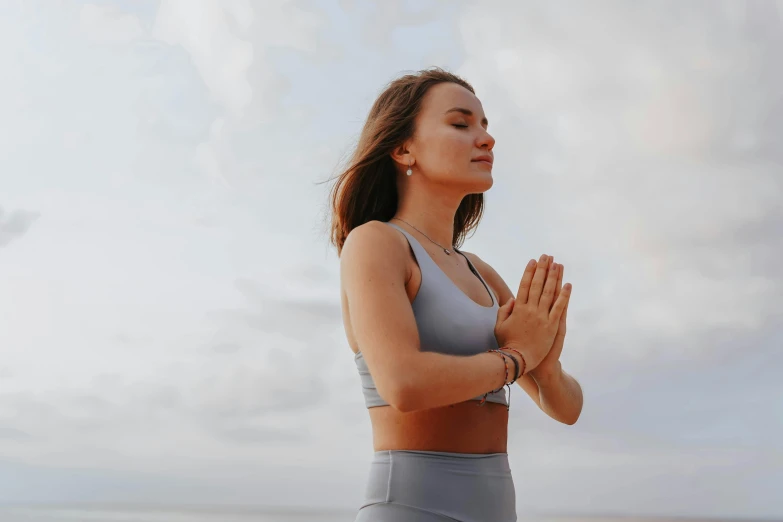 a woman is doing yoga on the beach, by Emma Andijewska, trending on pexels, renaissance, arms crossed on chest, wearing a vest top, blessing hands, ad image